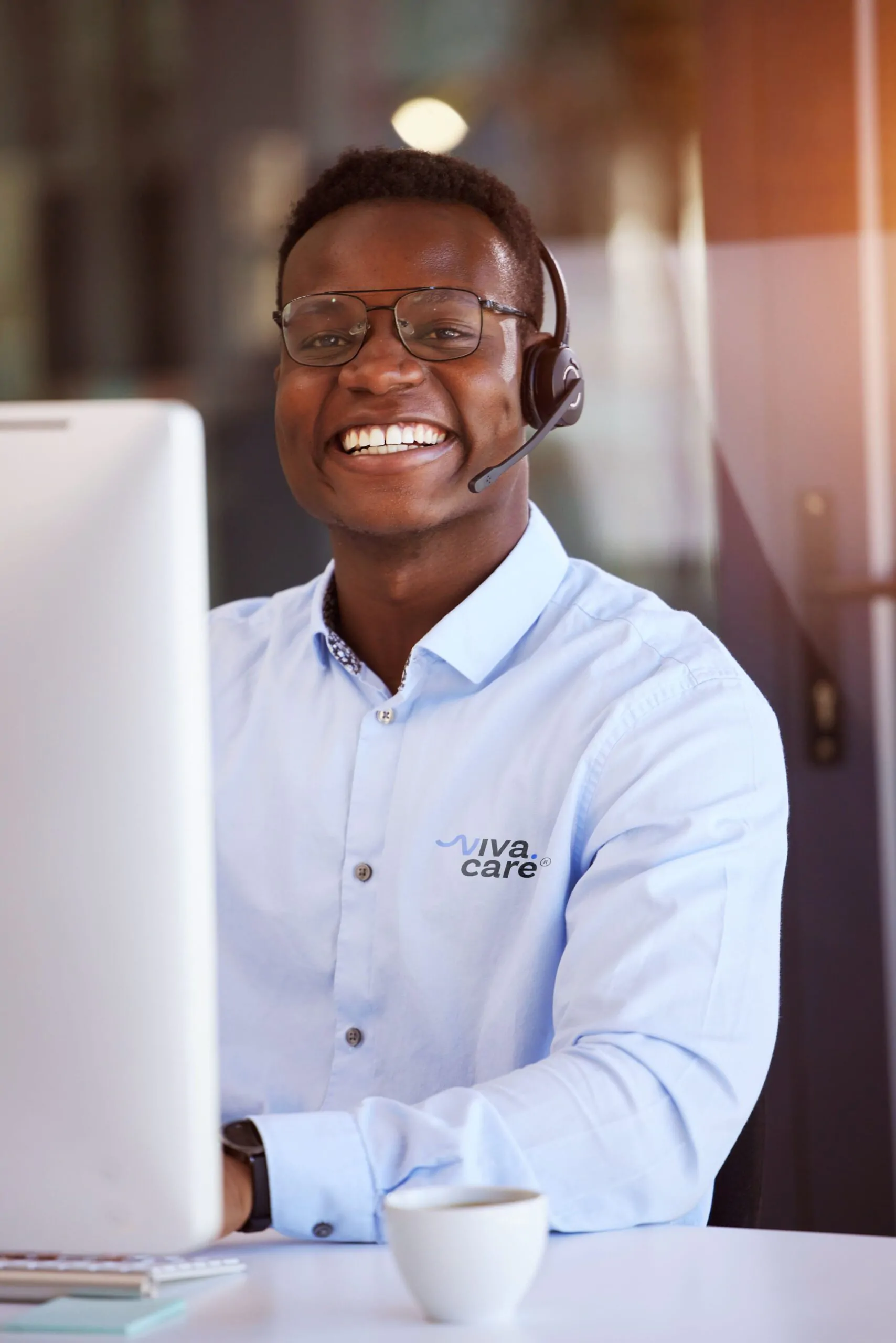 Atendente homem afro com fone tipo headset sorrindo. Simboliza bom atendimento e acolhimento. Viva Care Saúde